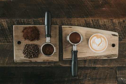 Two portafilters with a brewed cup of cappuccino placed side by side